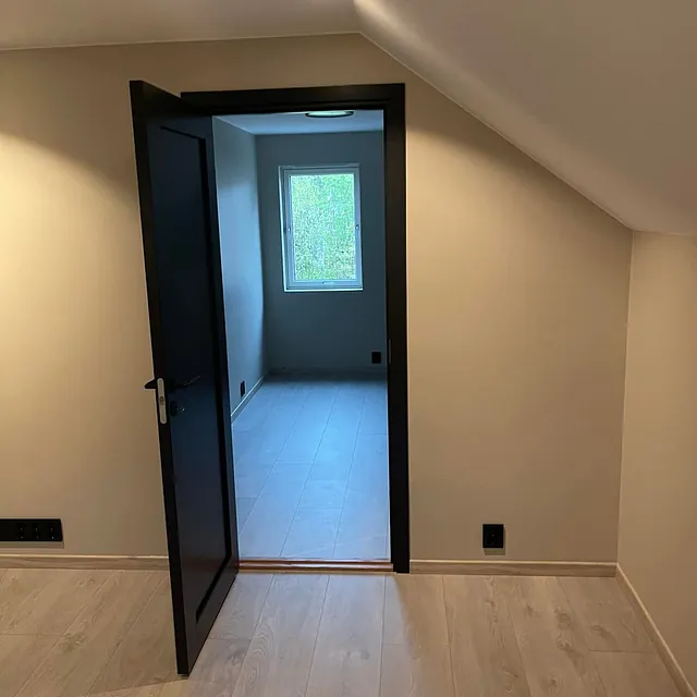 Nyoppusset rom med skråtak viser åpen svart dør