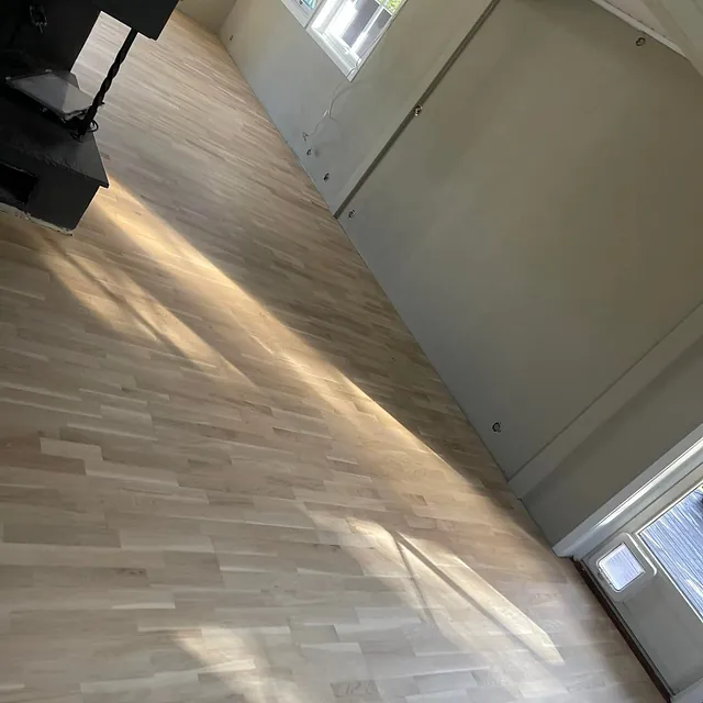 Nypusset og rent tregulv i stort rom med peis